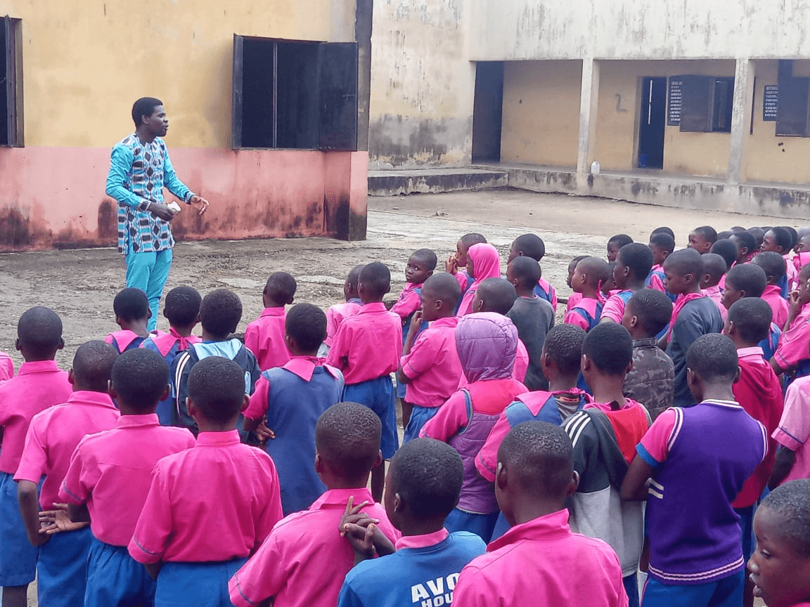 A man addressing the assembled pupils in the school yard.