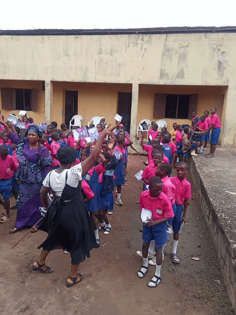 Pupils raising their new exercise books in the air during the distribution.